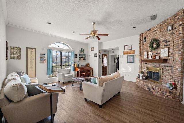 living room featuring a brick fireplace, ceiling fan, ornamental molding, a textured ceiling, and dark hardwood / wood-style flooring