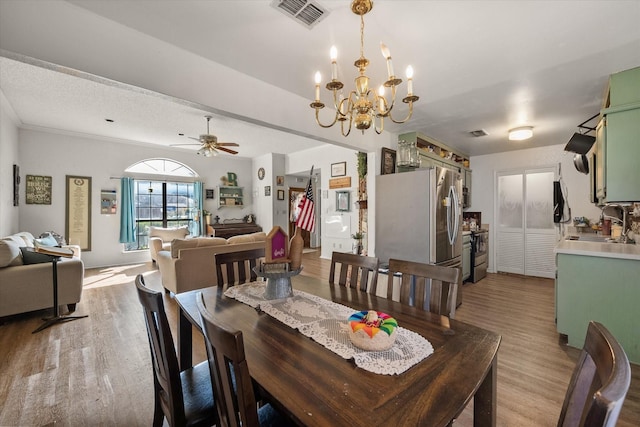 dining area with ceiling fan with notable chandelier, sink, and light hardwood / wood-style flooring