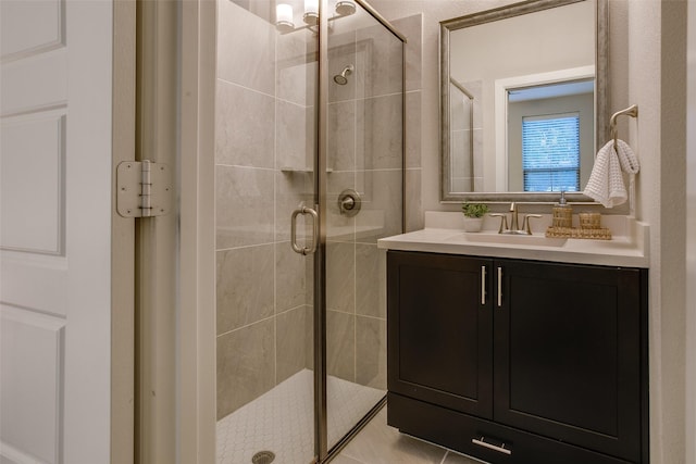 bathroom with a shower with door, vanity, and tile patterned flooring