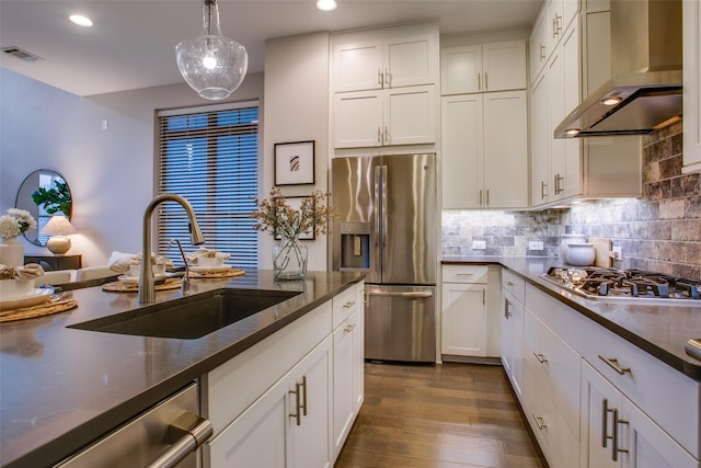 kitchen featuring sink, wall chimney exhaust hood, hanging light fixtures, stainless steel appliances, and white cabinets