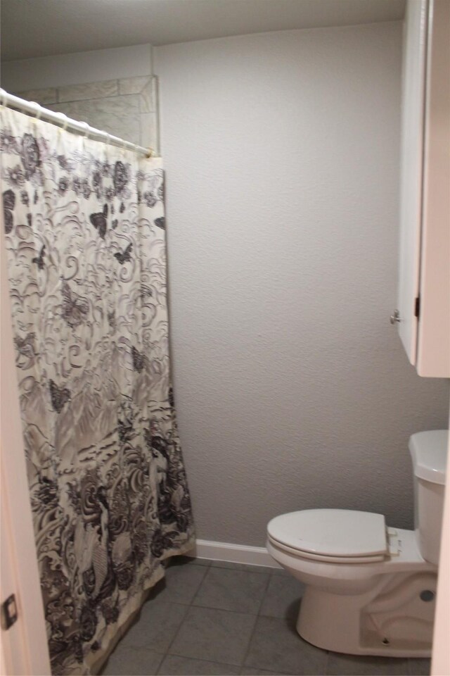 bathroom with tile patterned floors, a shower with shower curtain, and toilet