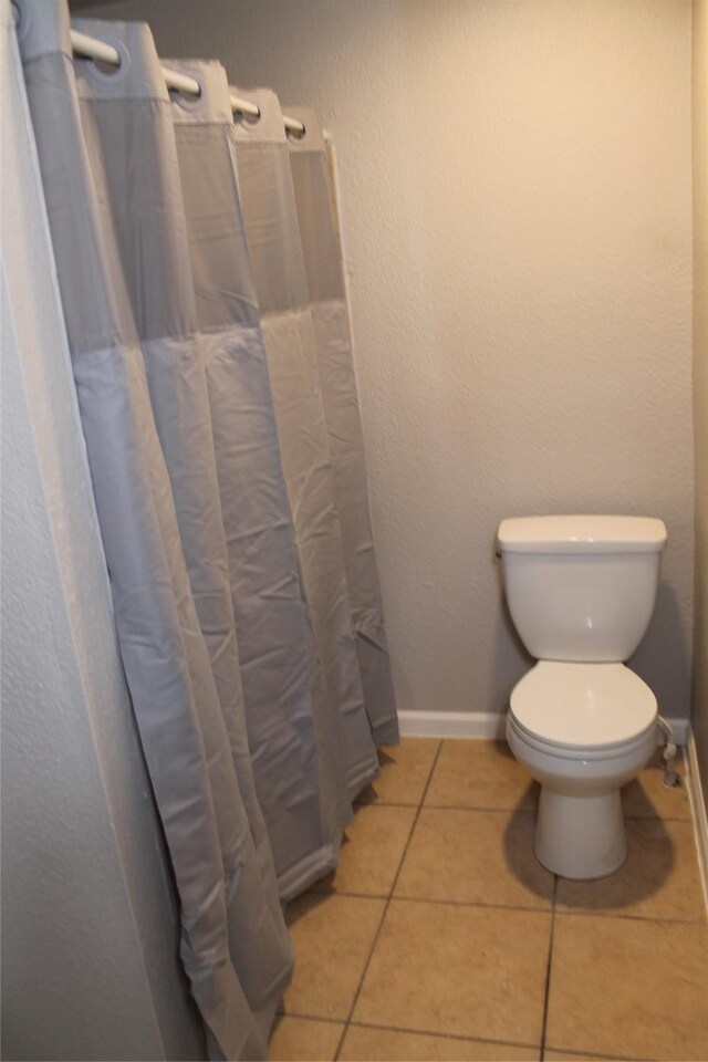 bathroom featuring tile patterned flooring, a shower with shower curtain, and toilet