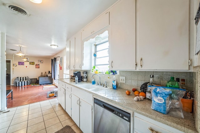 kitchen featuring dishwasher, white cabinets, light tile patterned flooring, and sink