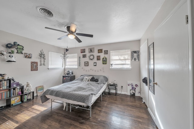 bedroom featuring ceiling fan, dark hardwood / wood-style floors, a textured ceiling, and multiple windows