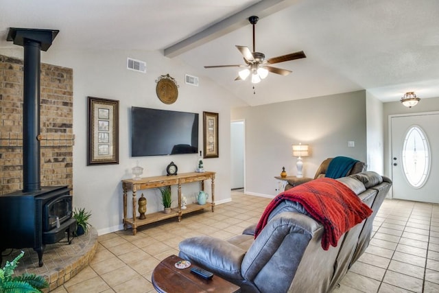 tiled living room featuring vaulted ceiling with beams, ceiling fan, and a wood stove