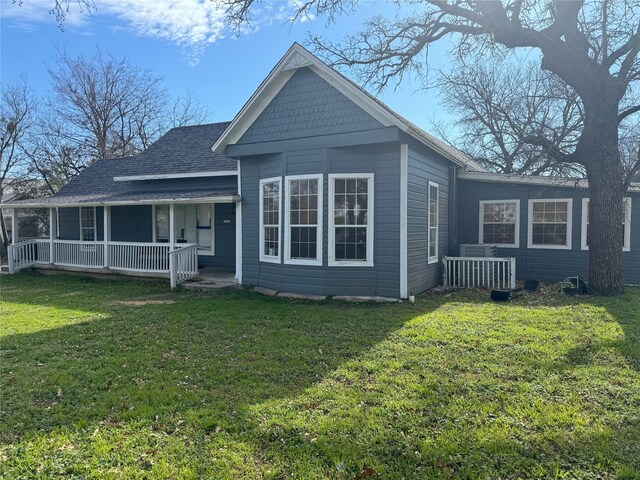 back of house with covered porch and a yard