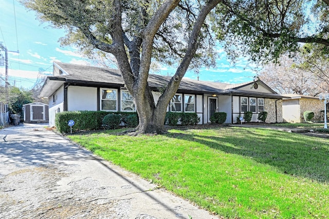 single story home with a front lawn and a shed