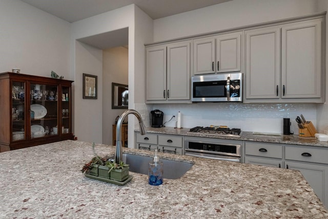 kitchen with gray cabinetry, backsplash, sink, and stainless steel appliances