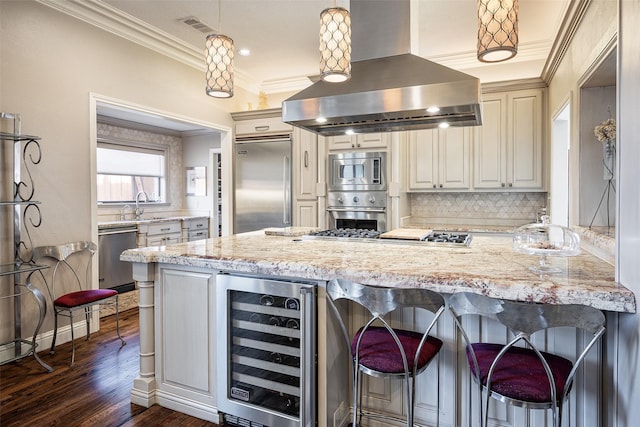 kitchen with light stone counters, pendant lighting, beverage cooler, and exhaust hood