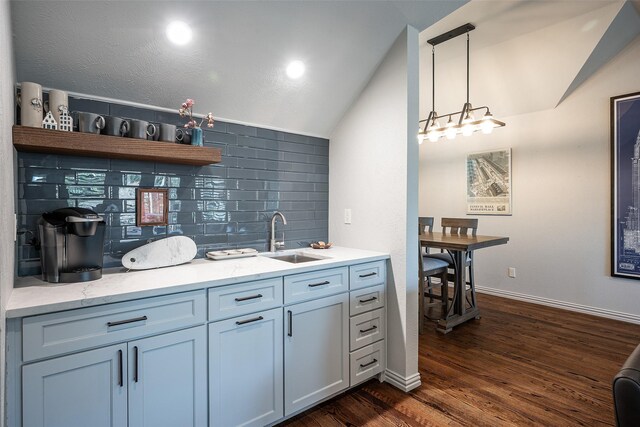 bar featuring lofted ceiling, dark wood-type flooring, sink, hanging light fixtures, and tasteful backsplash