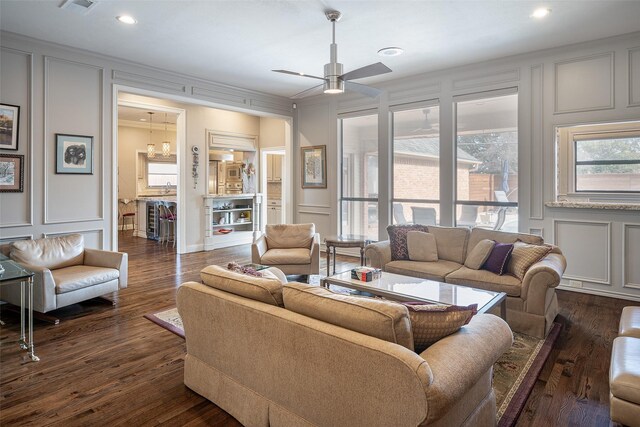 living room with dark hardwood / wood-style floors, a healthy amount of sunlight, ornamental molding, and ceiling fan