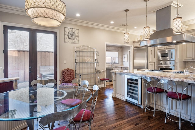 kitchen featuring light stone countertops, french doors, island exhaust hood, built in appliances, and pendant lighting