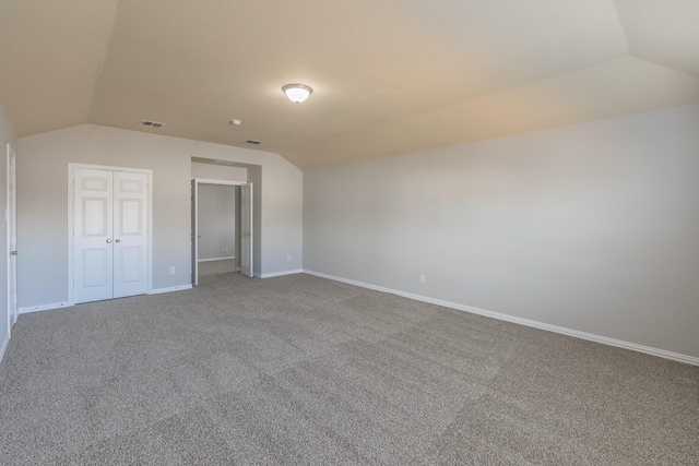 unfurnished bedroom with carpet floors, vaulted ceiling, and a closet