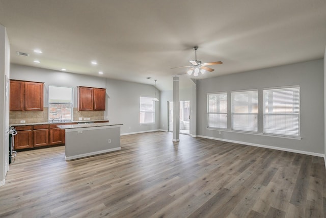 kitchen featuring tasteful backsplash, ceiling fan, a kitchen island, and light wood-type flooring