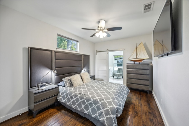 bedroom featuring ceiling fan, a barn door, and dark hardwood / wood-style floors