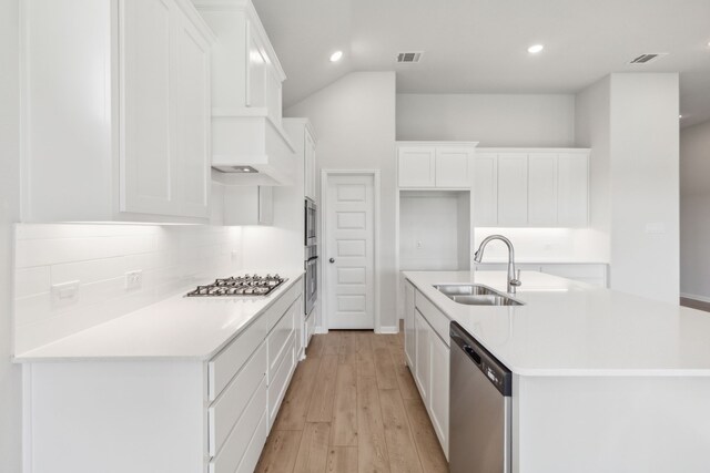 kitchen with sink, decorative backsplash, an island with sink, appliances with stainless steel finishes, and white cabinetry