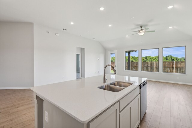 kitchen with stainless steel dishwasher, ceiling fan, a kitchen island with sink, sink, and light hardwood / wood-style floors