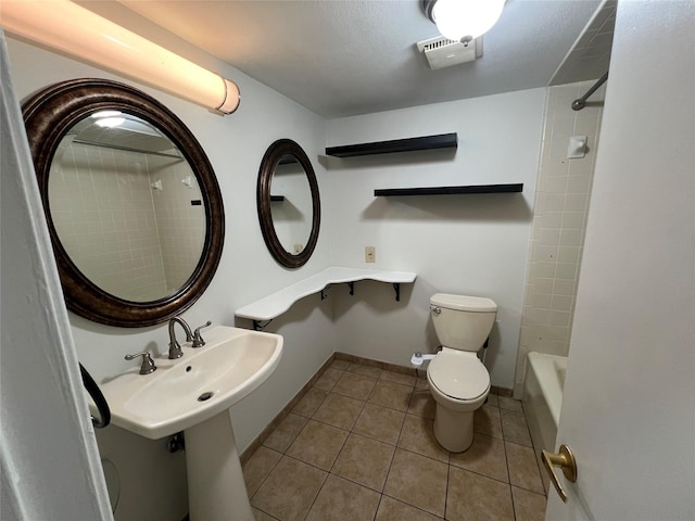 bathroom with tile patterned flooring, tiled shower / bath, and toilet