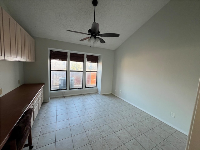 spare room with ceiling fan, lofted ceiling, a textured ceiling, and light tile patterned floors