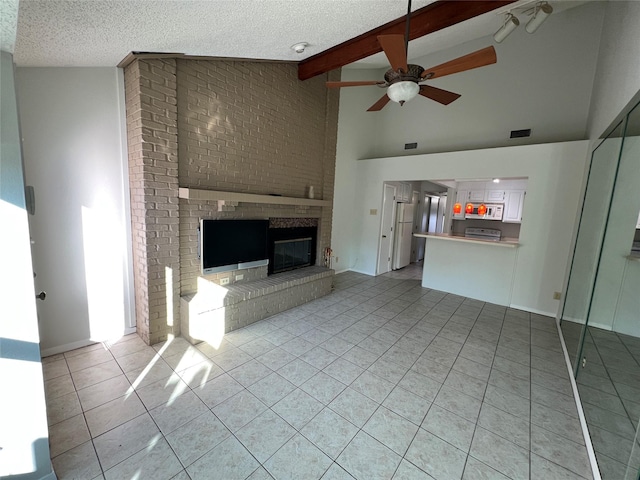 unfurnished living room featuring lofted ceiling with beams, light tile patterned floors, ceiling fan, a brick fireplace, and a textured ceiling