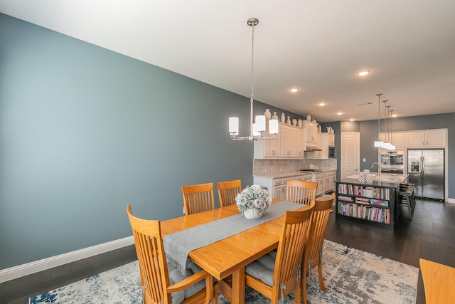 dining room with a chandelier, sink, and dark wood-type flooring