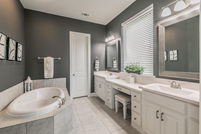 bathroom featuring tile patterned flooring, vanity, and tiled bath