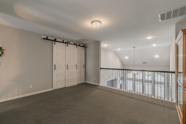 carpeted spare room with a barn door and lofted ceiling