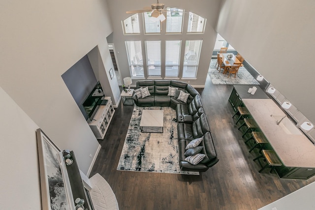 living room featuring a towering ceiling, dark hardwood / wood-style floors, and ceiling fan