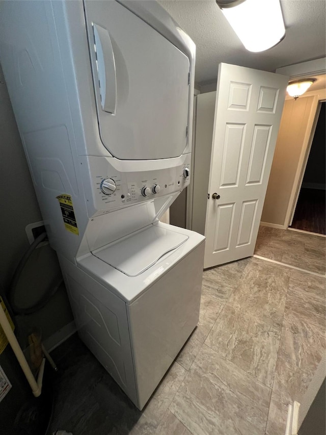 laundry room featuring stacked washing maching and dryer and a textured ceiling