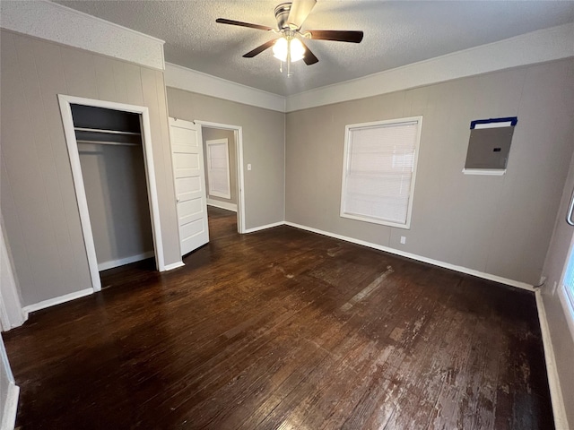 unfurnished bedroom with ceiling fan, electric panel, a textured ceiling, dark hardwood / wood-style flooring, and a closet