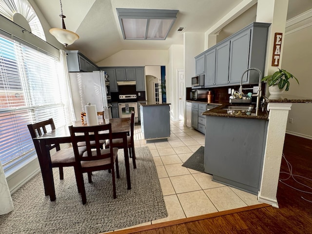 dining area with light tile patterned floors, vaulted ceiling, and sink