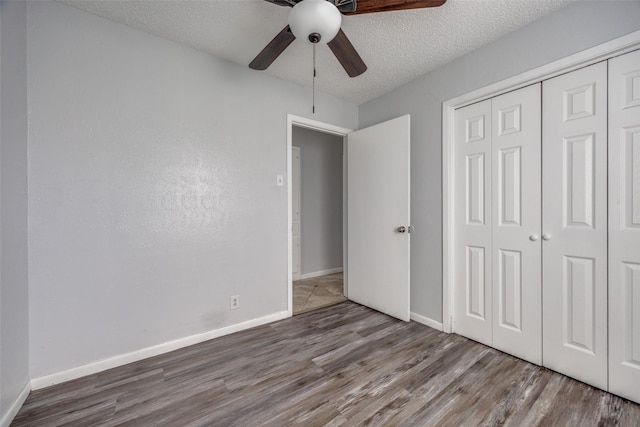 unfurnished bedroom with hardwood / wood-style flooring, ceiling fan, a closet, and a textured ceiling