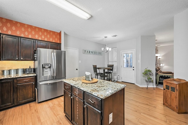 kitchen featuring dark brown cabinets, stainless steel fridge with ice dispenser, a center island, and decorative light fixtures