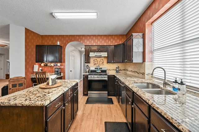 kitchen featuring a textured ceiling, light stone countertops, sink, and stainless steel gas range