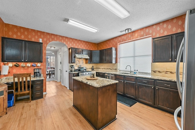 kitchen featuring a center island, sink, light stone countertops, and stainless steel appliances