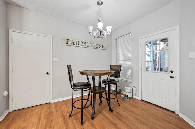 dining area featuring a textured ceiling, hardwood / wood-style flooring, and a notable chandelier