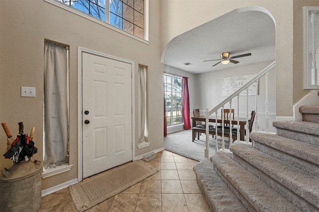 tiled foyer entrance with ceiling fan and a textured ceiling