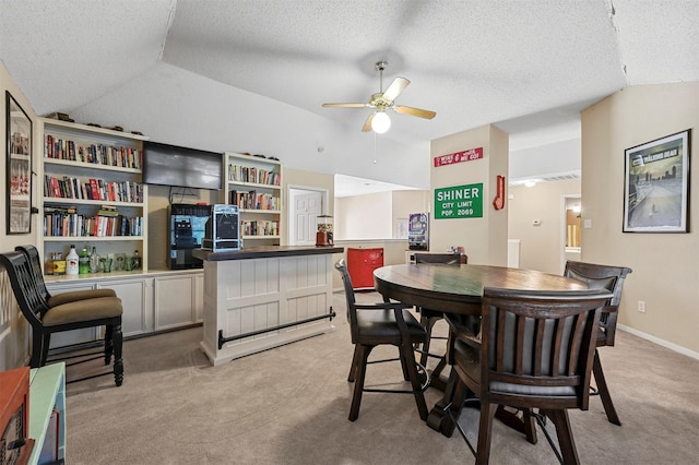 carpeted dining room with a textured ceiling, indoor bar, ceiling fan, and lofted ceiling