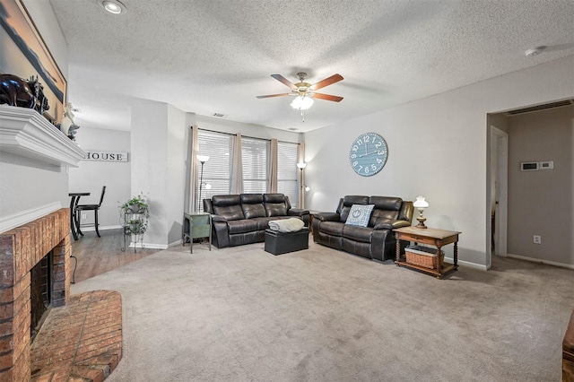 living room with a textured ceiling, ceiling fan, carpet floors, and a fireplace