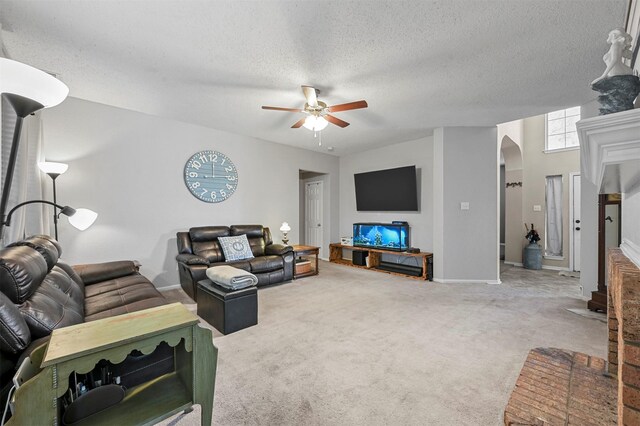 living room with ceiling fan, carpet floors, and a textured ceiling