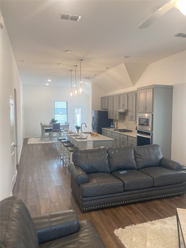 living room with dark hardwood / wood-style floors, lofted ceiling, and sink