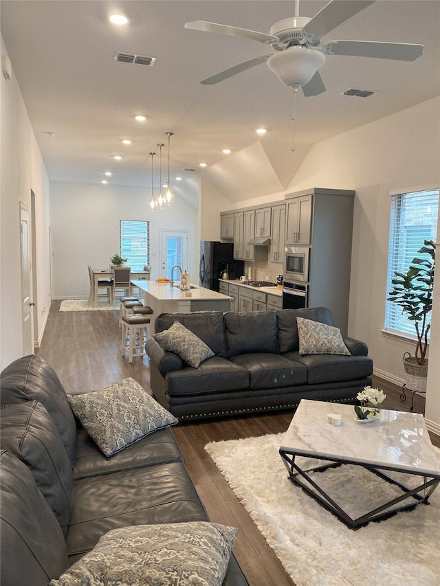 living room with ceiling fan, dark hardwood / wood-style flooring, sink, and vaulted ceiling