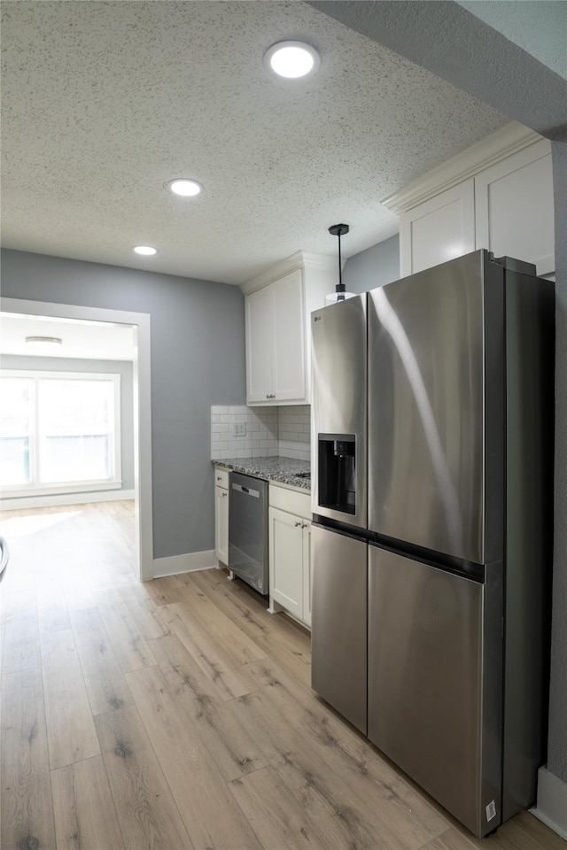 kitchen featuring pendant lighting, light hardwood / wood-style flooring, backsplash, stainless steel appliances, and white cabinets