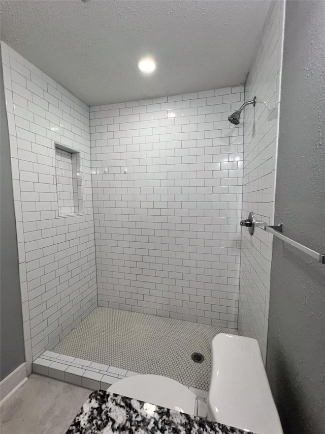 bathroom with tiled shower and a textured ceiling