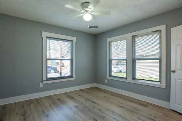 empty room with a textured ceiling, a healthy amount of sunlight, and light wood-type flooring