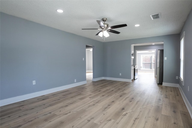 unfurnished room with ceiling fan, light hardwood / wood-style flooring, and a textured ceiling