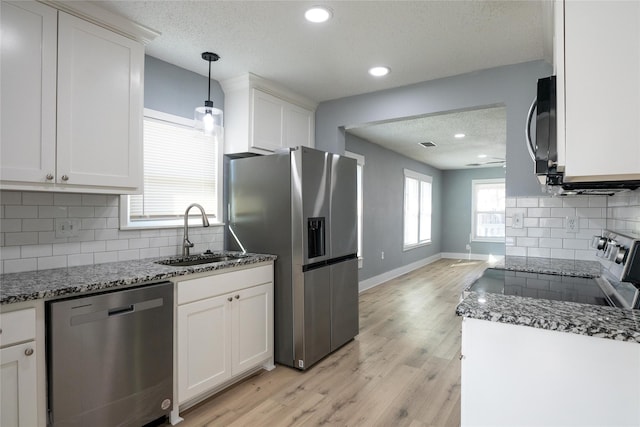 kitchen with sink, decorative light fixtures, light hardwood / wood-style flooring, appliances with stainless steel finishes, and white cabinets