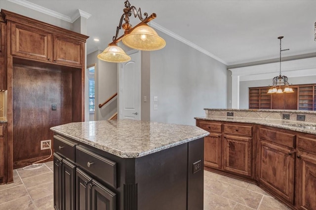 kitchen with light stone countertops, hanging light fixtures, a center island, and ornamental molding