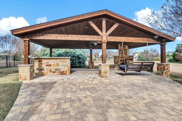 view of patio / terrace featuring exterior fireplace, ceiling fan, and a gazebo