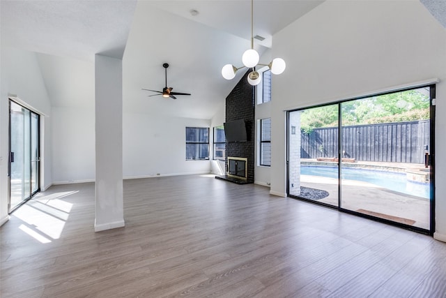 unfurnished living room featuring a fireplace, wood-type flooring, high vaulted ceiling, and ceiling fan